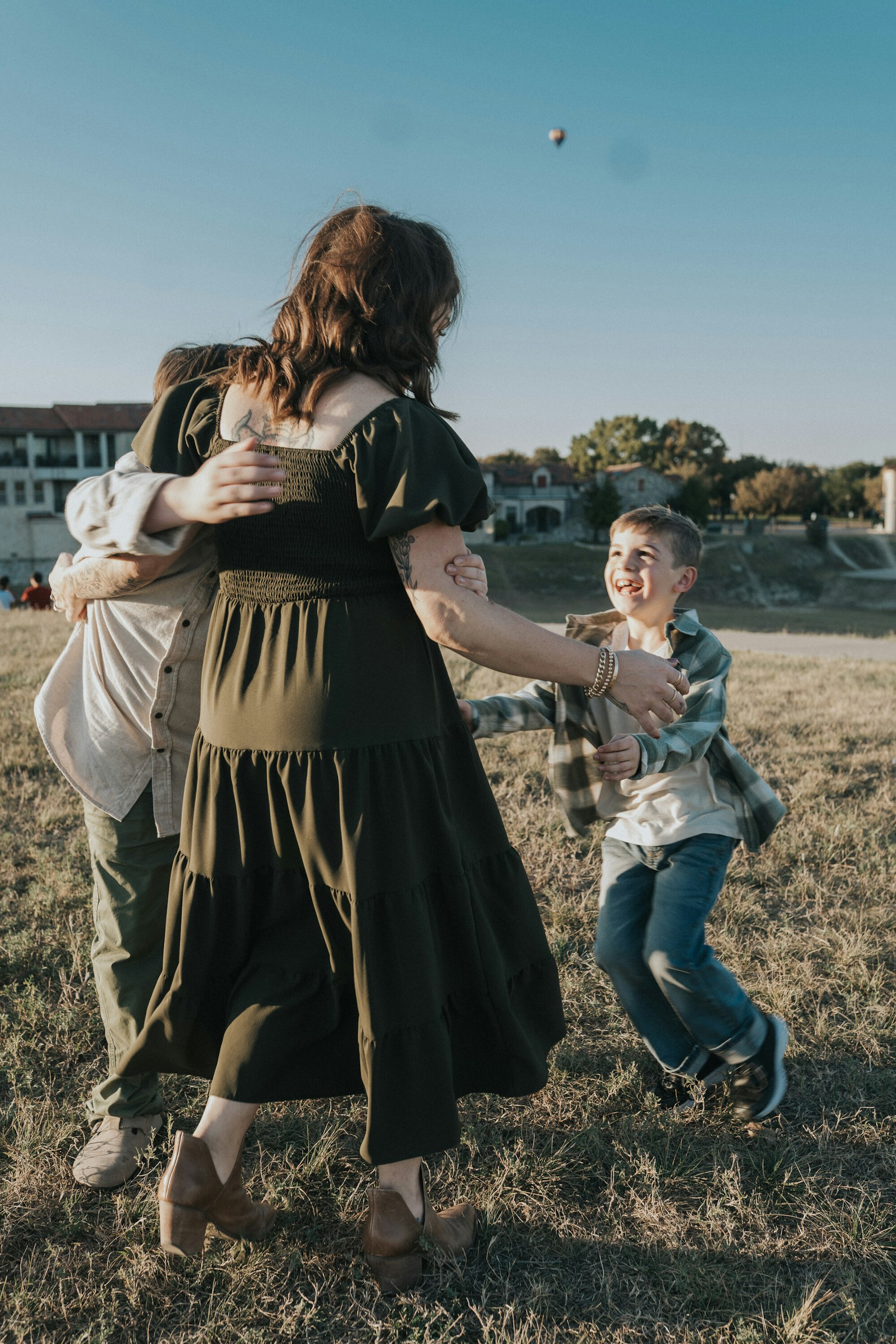 Mom twirling with her sons on the lakeshore during a lakeside family session