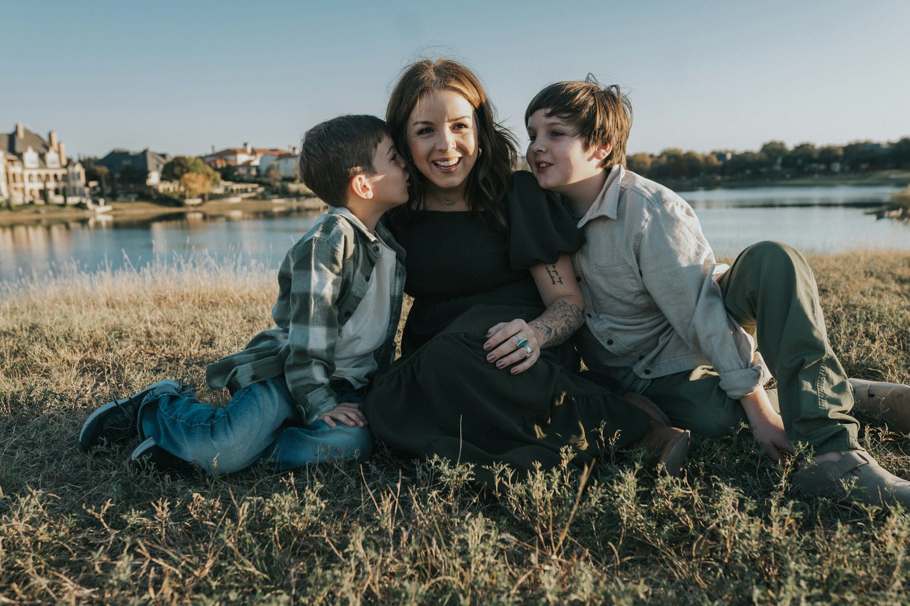 Mom sitting with her boys, lake and houses behind them during a lakeside family session