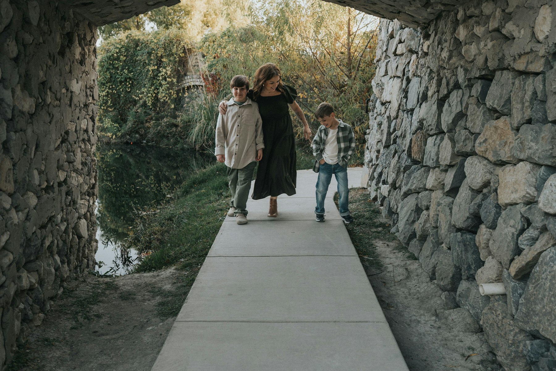 Mom and boys walking through a stone tunnel during a lakeside family session