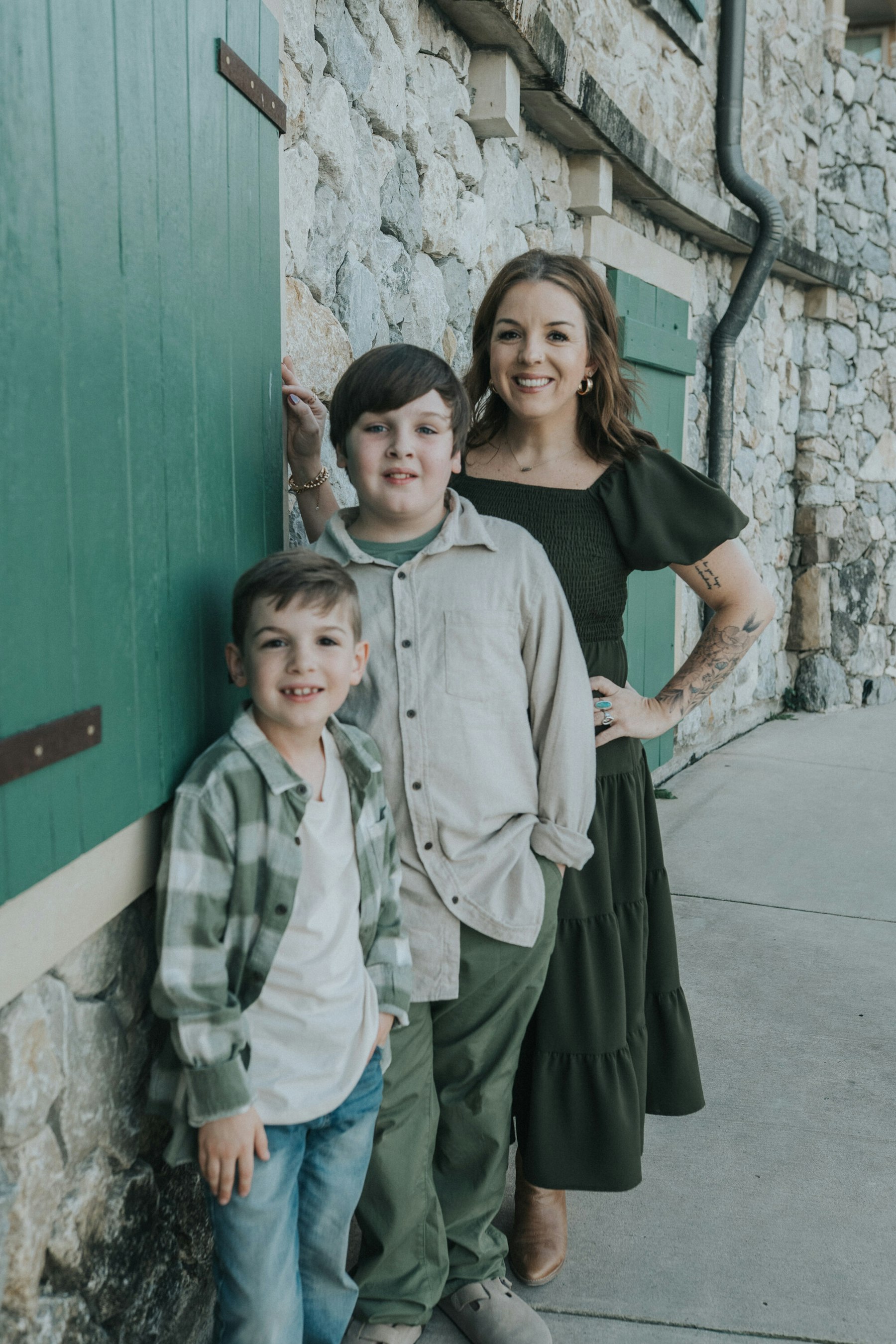 Mom and her boys posed by a green door on a stone building during a lakeside family session