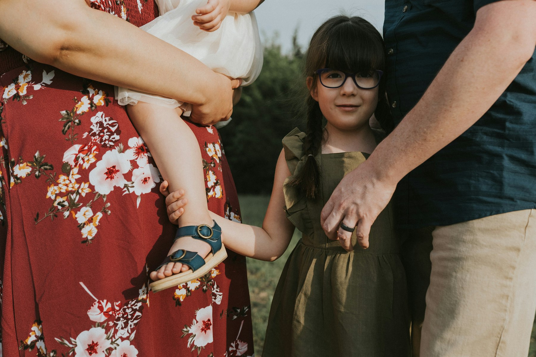 Toddler's sandal in mom's hand and dad holding his daughter's hand, close up during a family session
