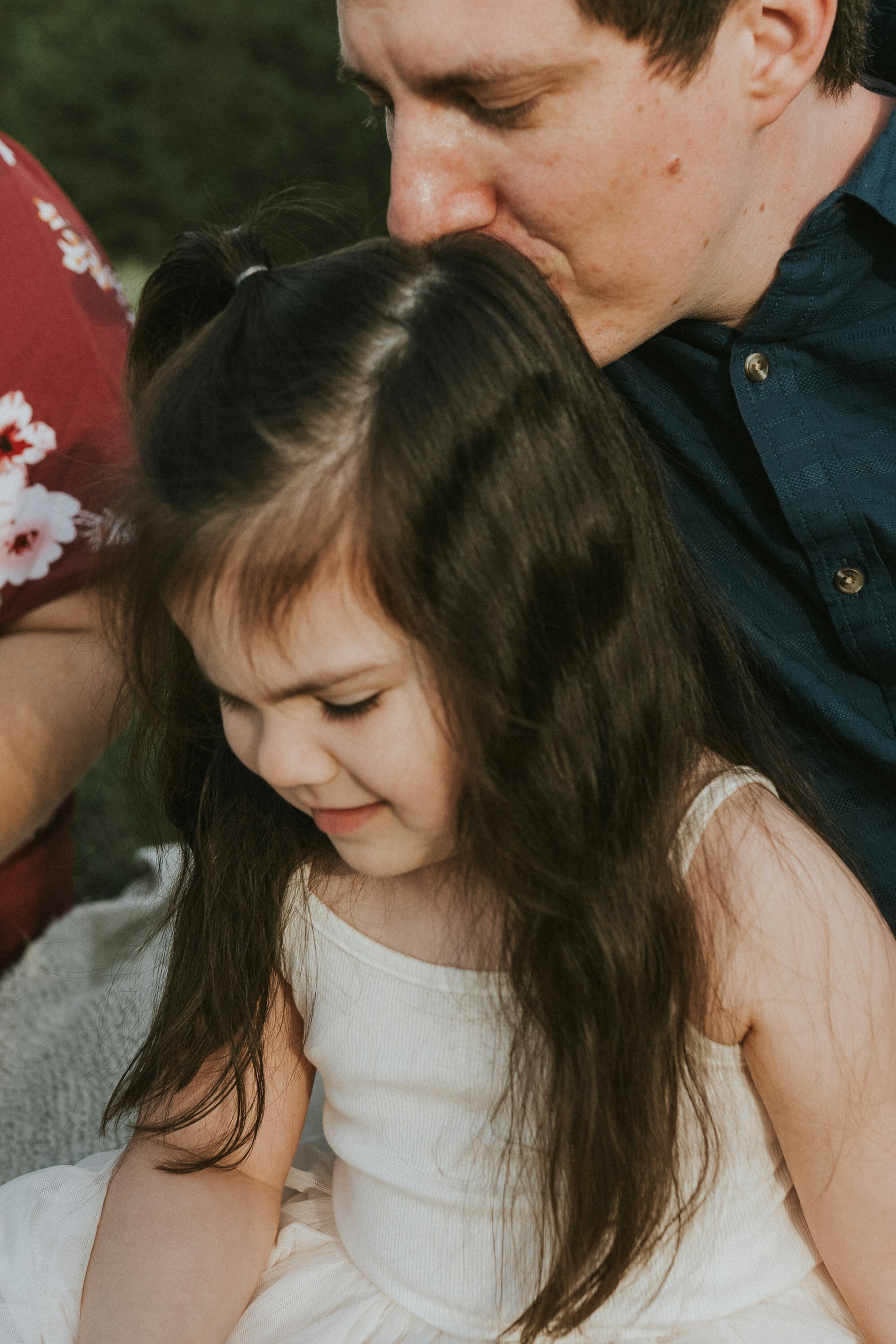 Dad kissing the top of his daughter's head during a family session