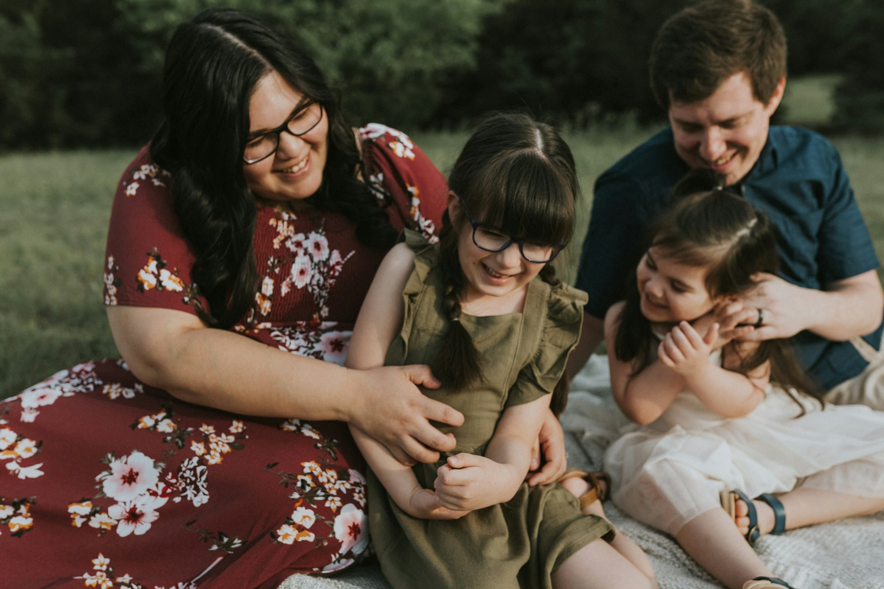 Family sitting in the grass, dad tickling the girls during a family session