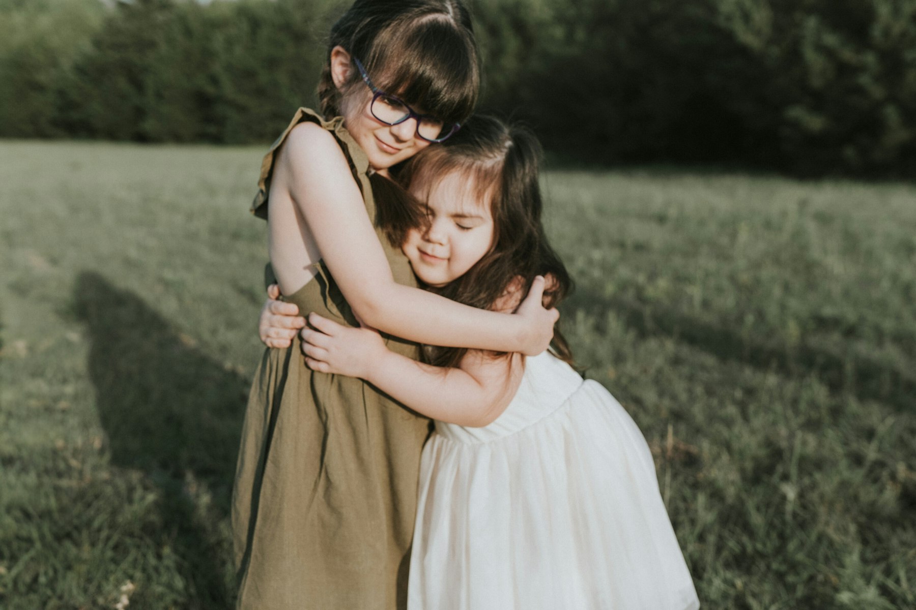 Sisters hugging in the field during a family session