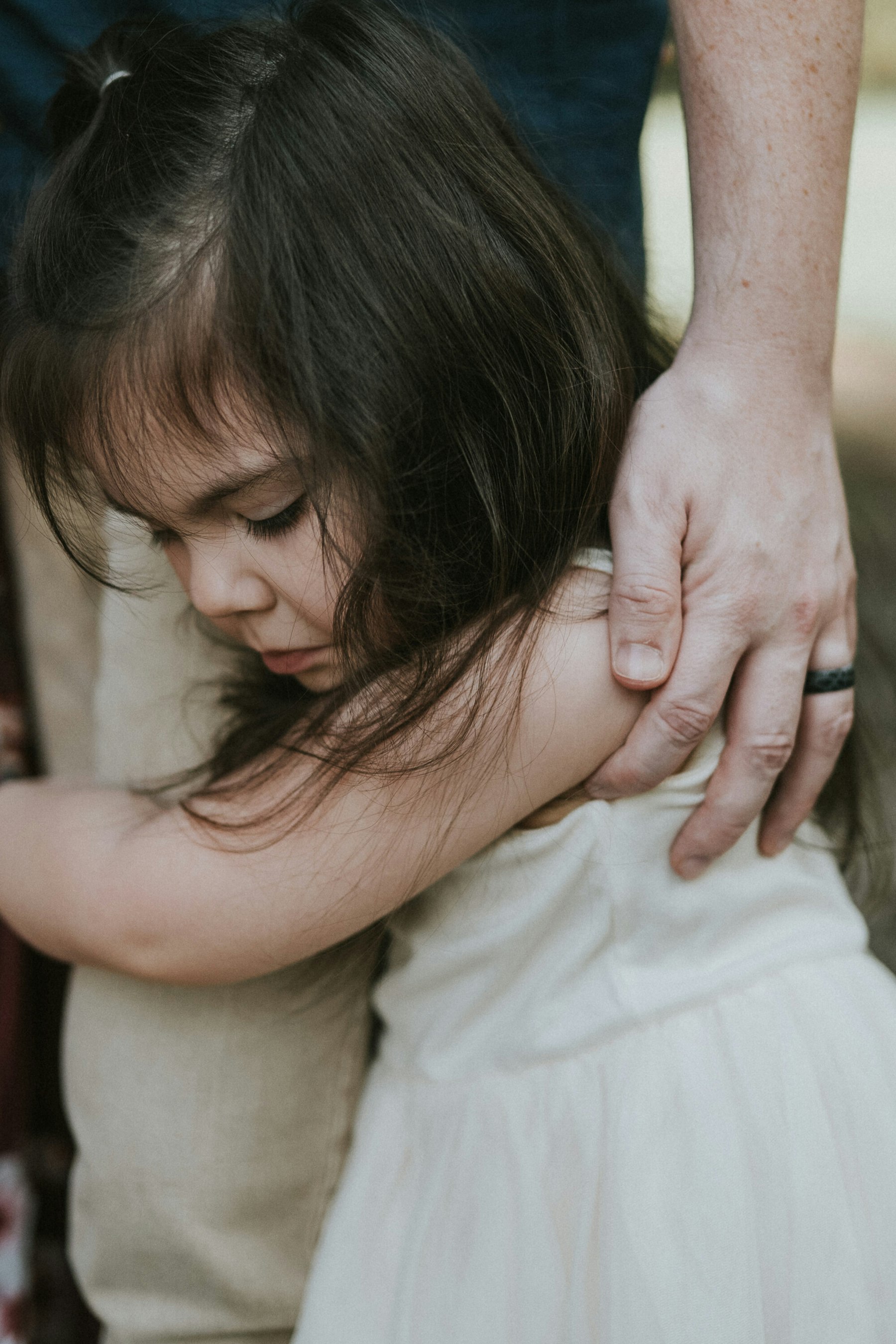 Daughter hugging her dad's arm, close up during a family session