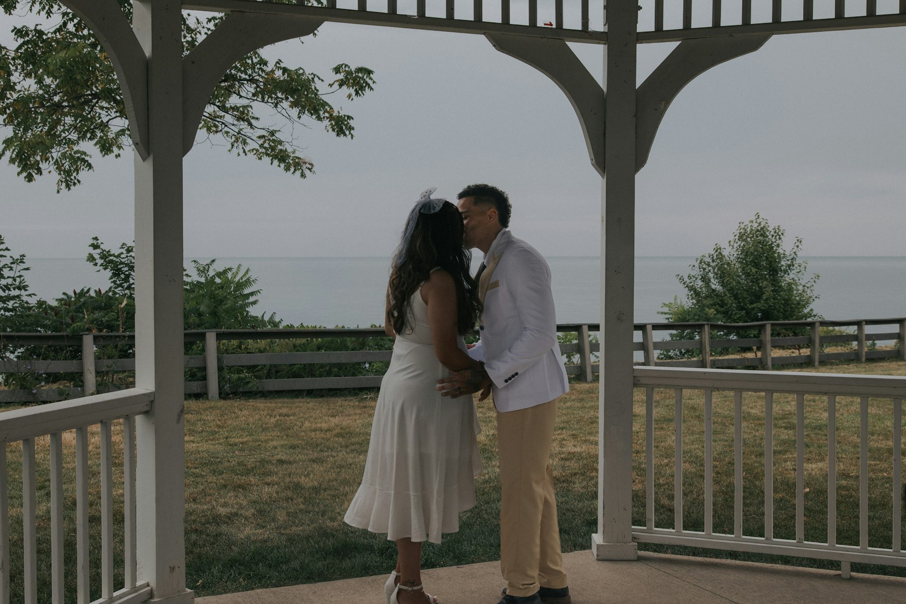 Bride and groom kissing under the lakeside gazebo, Lake Erie behind them at a Veterans Memorial Park wedding in Avon Lake, Ohio