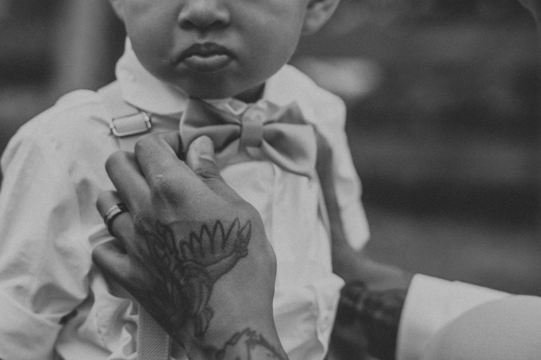 Black and white close up of the groom straightening his son's bow tie at a Veterans Memorial Park wedding in Avon Lake, Ohio