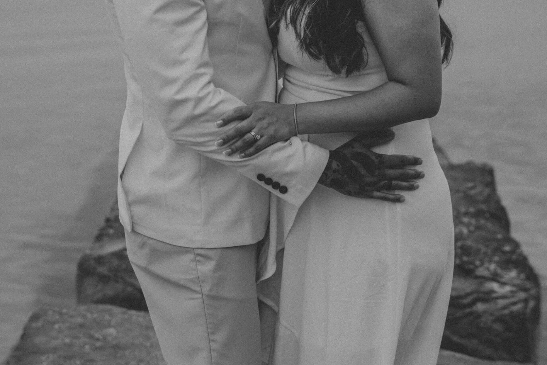 Black and white photo of the couple embracing on the breakwall at a Veterans Memorial Park wedding in Avon Lake, Ohio