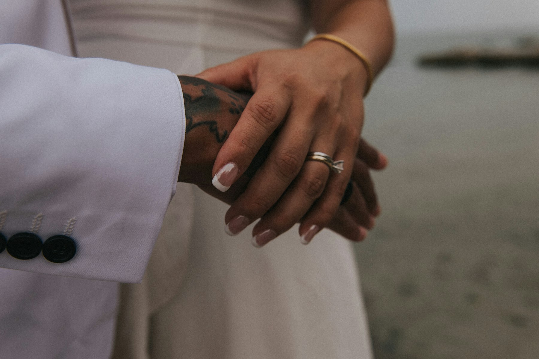 Close up of the couple's hands and wedding rings with the lake behind at a Veterans Memorial Park wedding in Avon Lake, Ohio