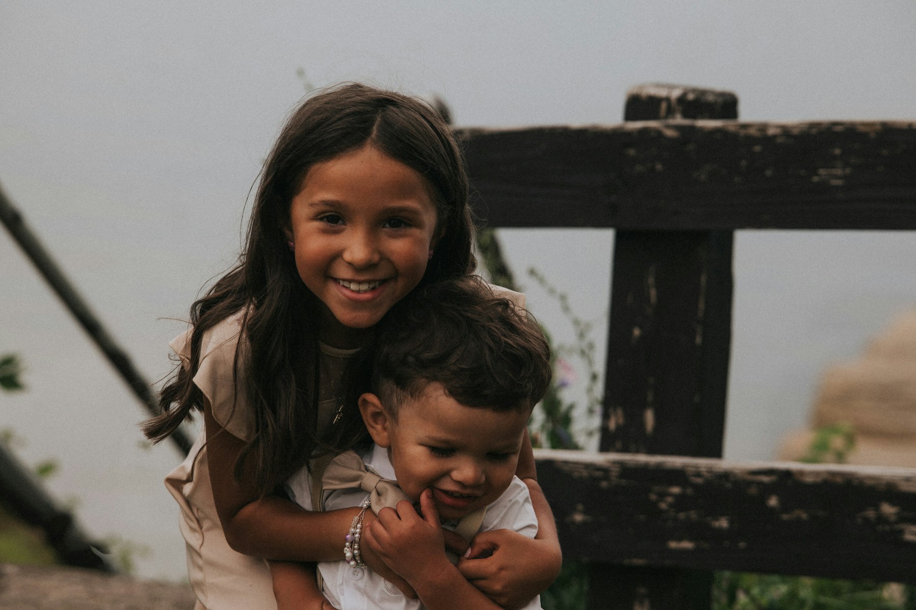 Big sister hugging her little brother by the wooden fence at a Veterans Memorial Park wedding in Avon Lake, Ohio