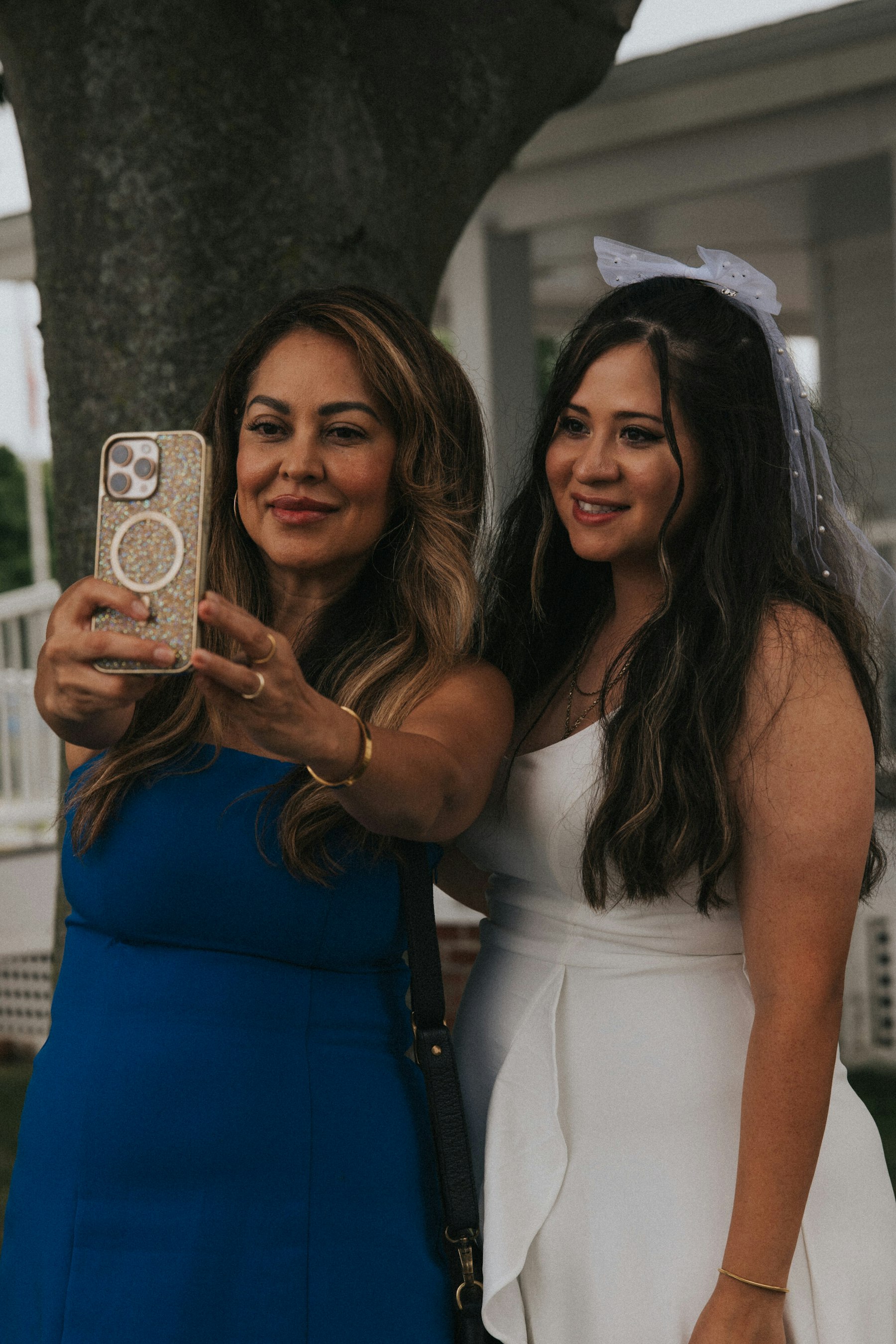 Bride taking a selfie with her mom under the trees at a Veterans Memorial Park wedding in Avon Lake, Ohio