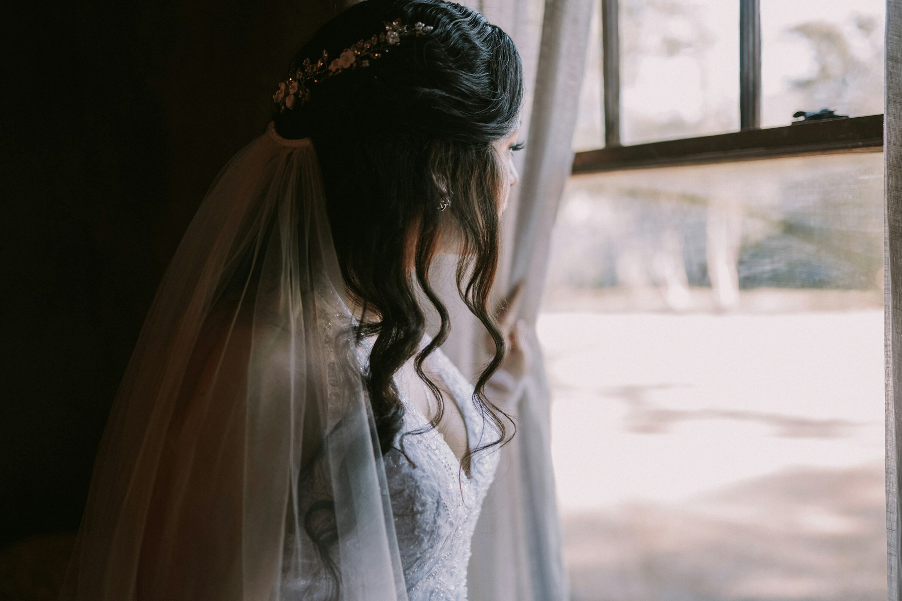 Bride in her veil at the window before the ceremony at a garden wedding