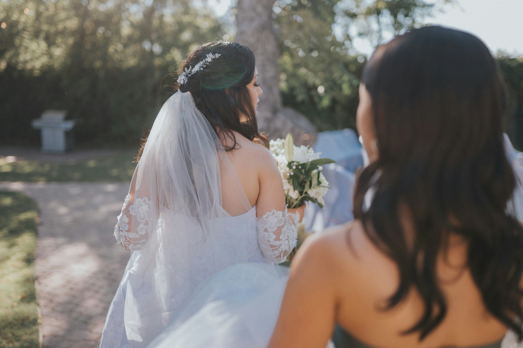 Bride walking toward the ceremony, seen from behind at a garden wedding