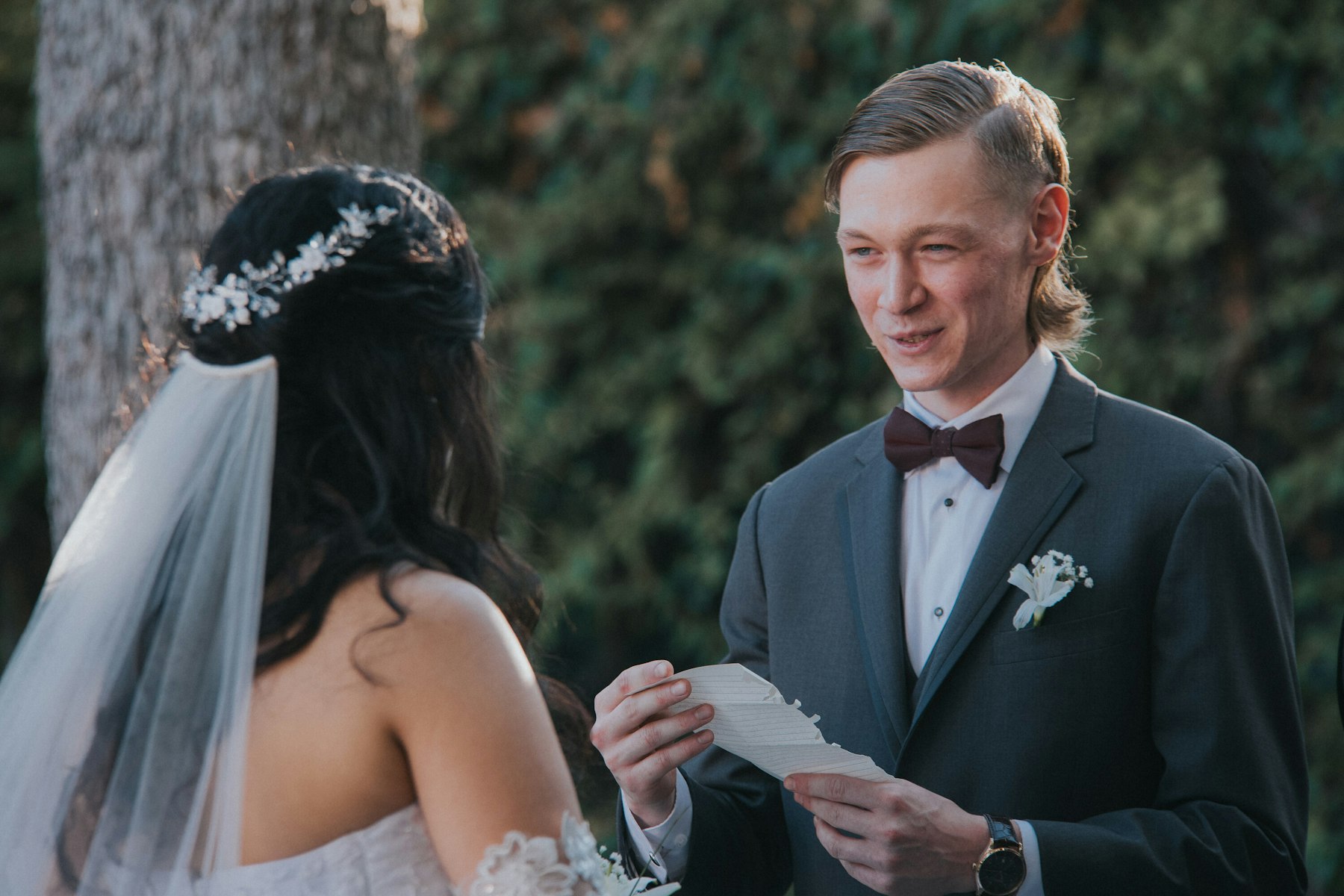 Groom reading his vows to the bride in her flower crown at a garden wedding