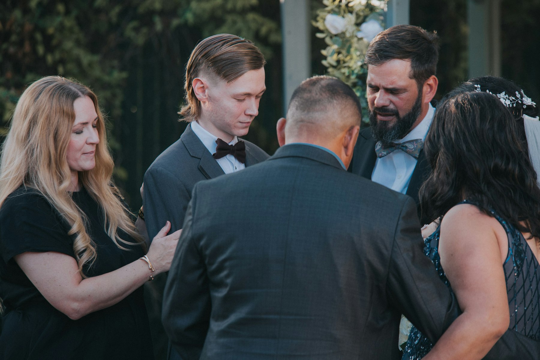Family embracing the groom after the ceremony at a garden wedding