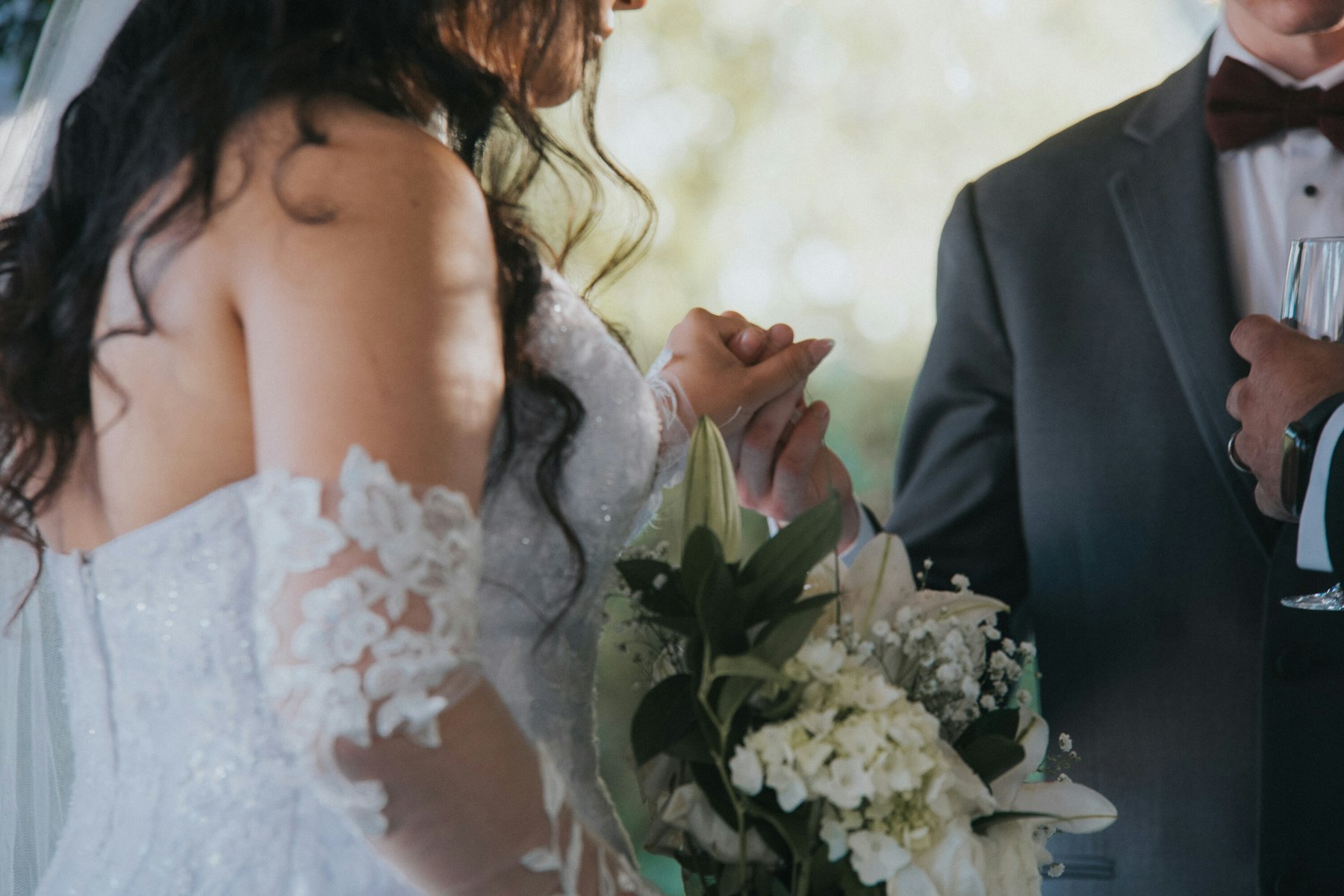 Bride holding the groom's hand during the ceremony at a garden wedding