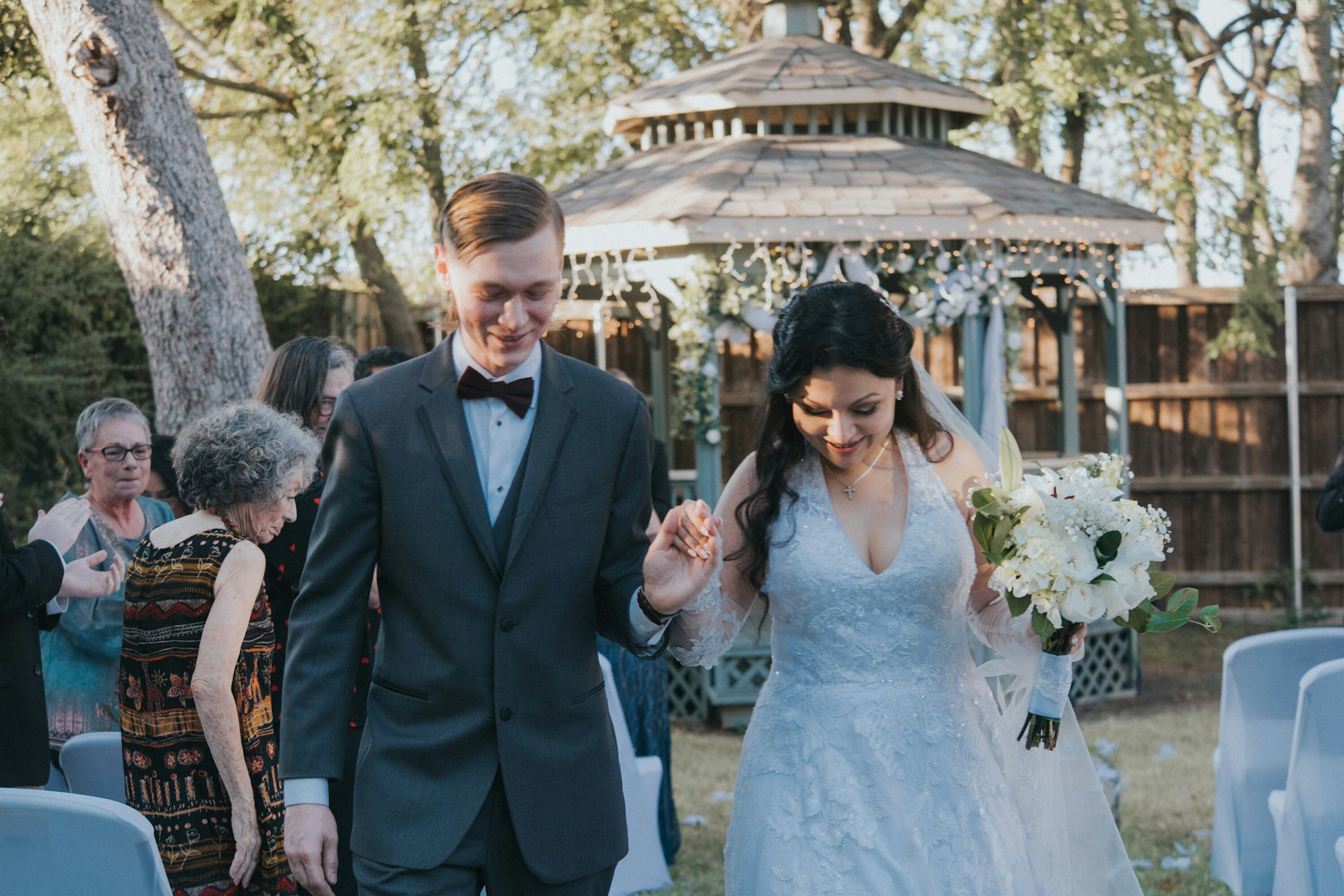 Bride and groom walking back down the aisle past the gazebo at a garden wedding
