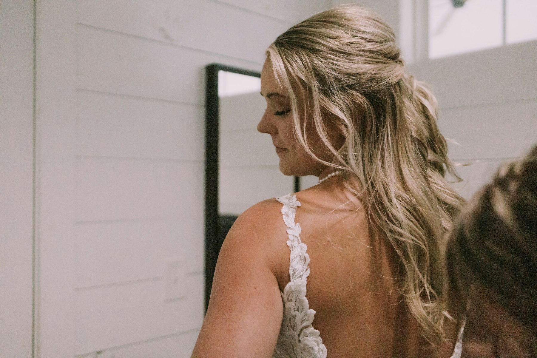 Bride looking over her shoulder while getting ready at a white barn wedding