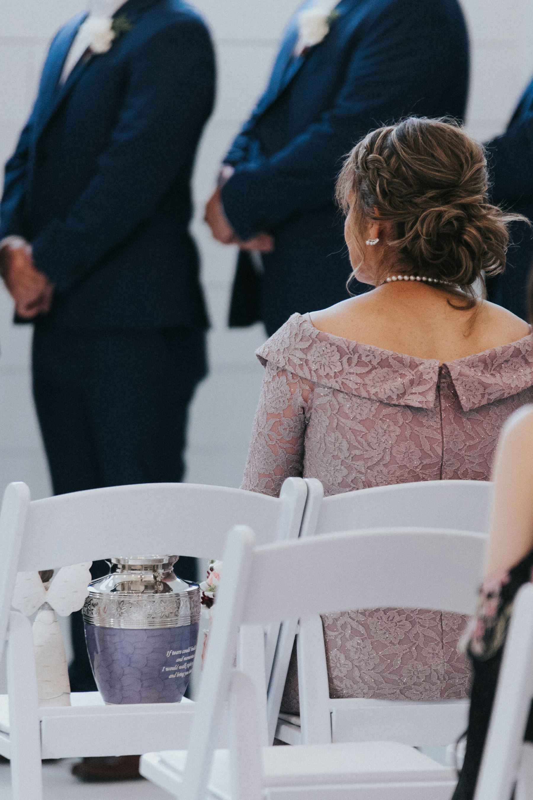 Mother of the groom seated at the ceremony at a white barn wedding