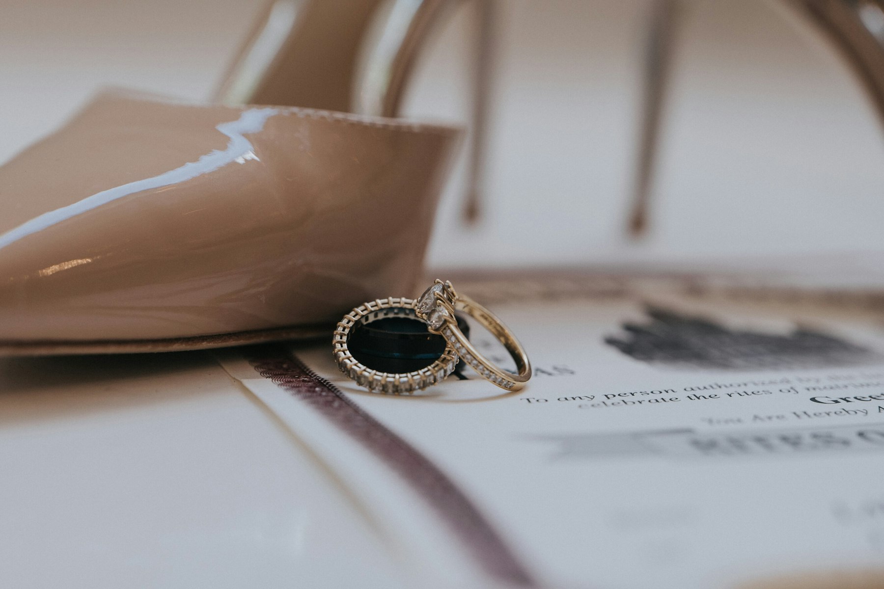 Bride's shoes and rings on the invitation suite at a white barn wedding