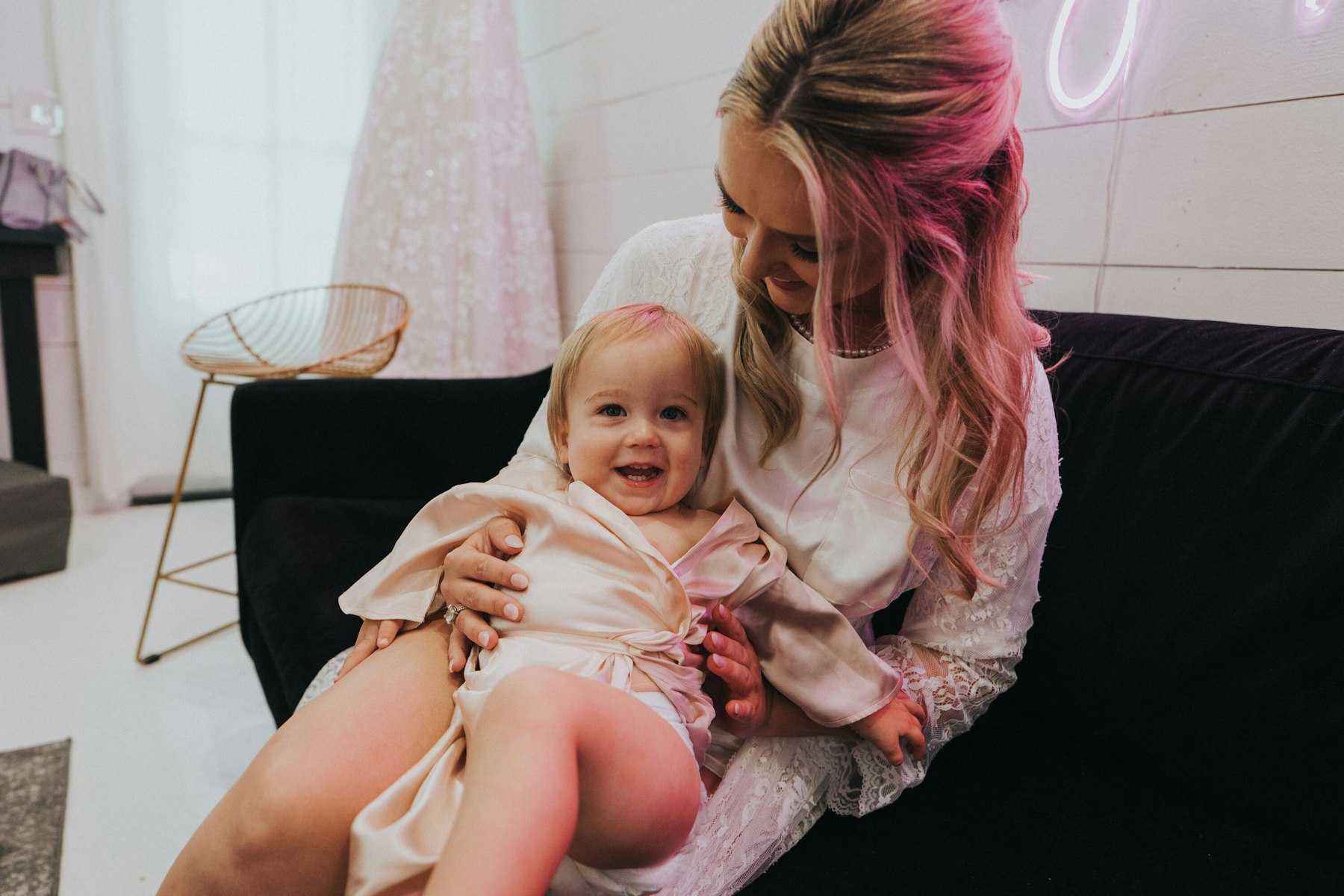 Bride holding a baby in the bridal suite at a white barn wedding