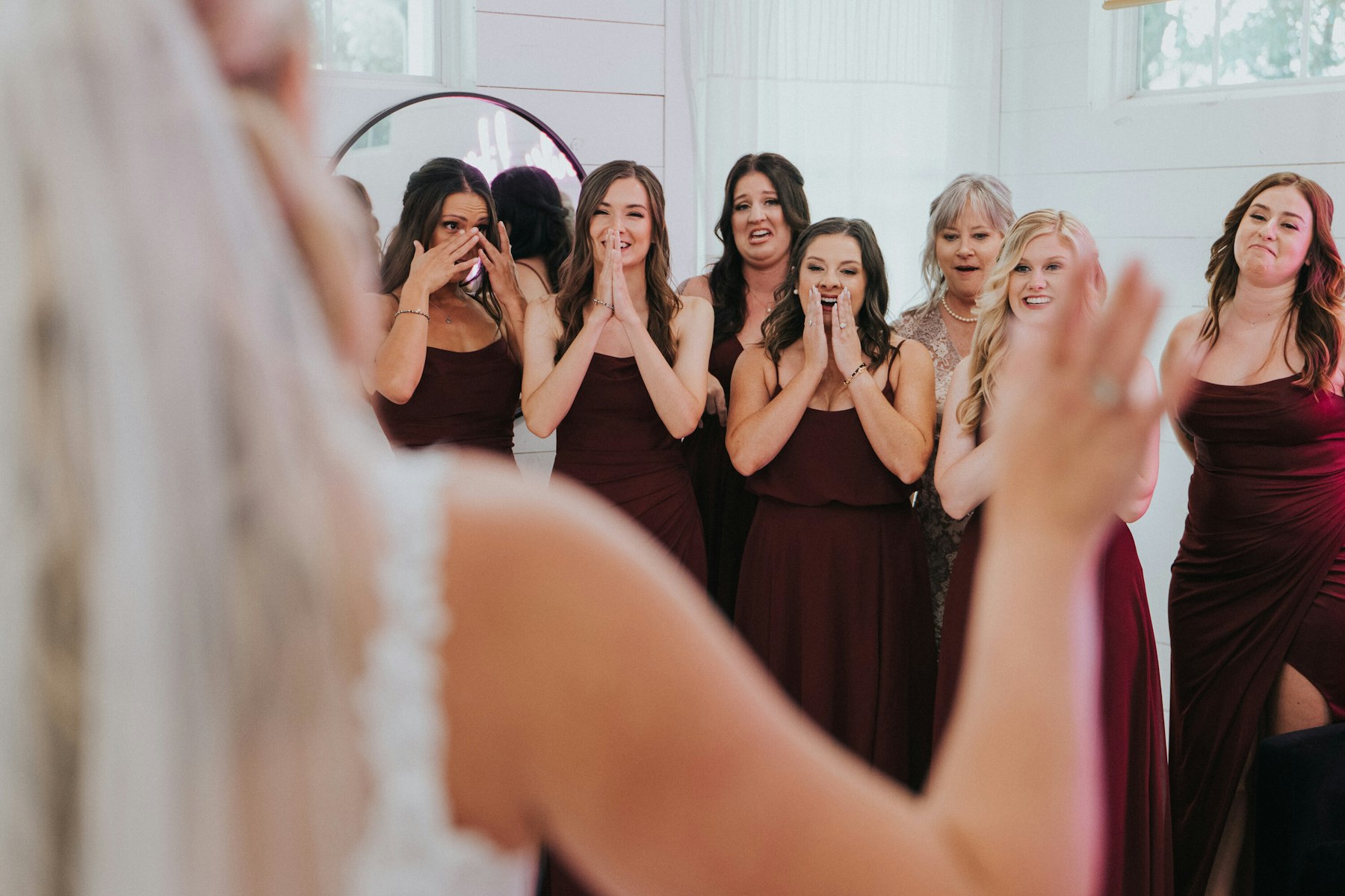 Bridesmaids reacting to the bride's first look at a white barn wedding