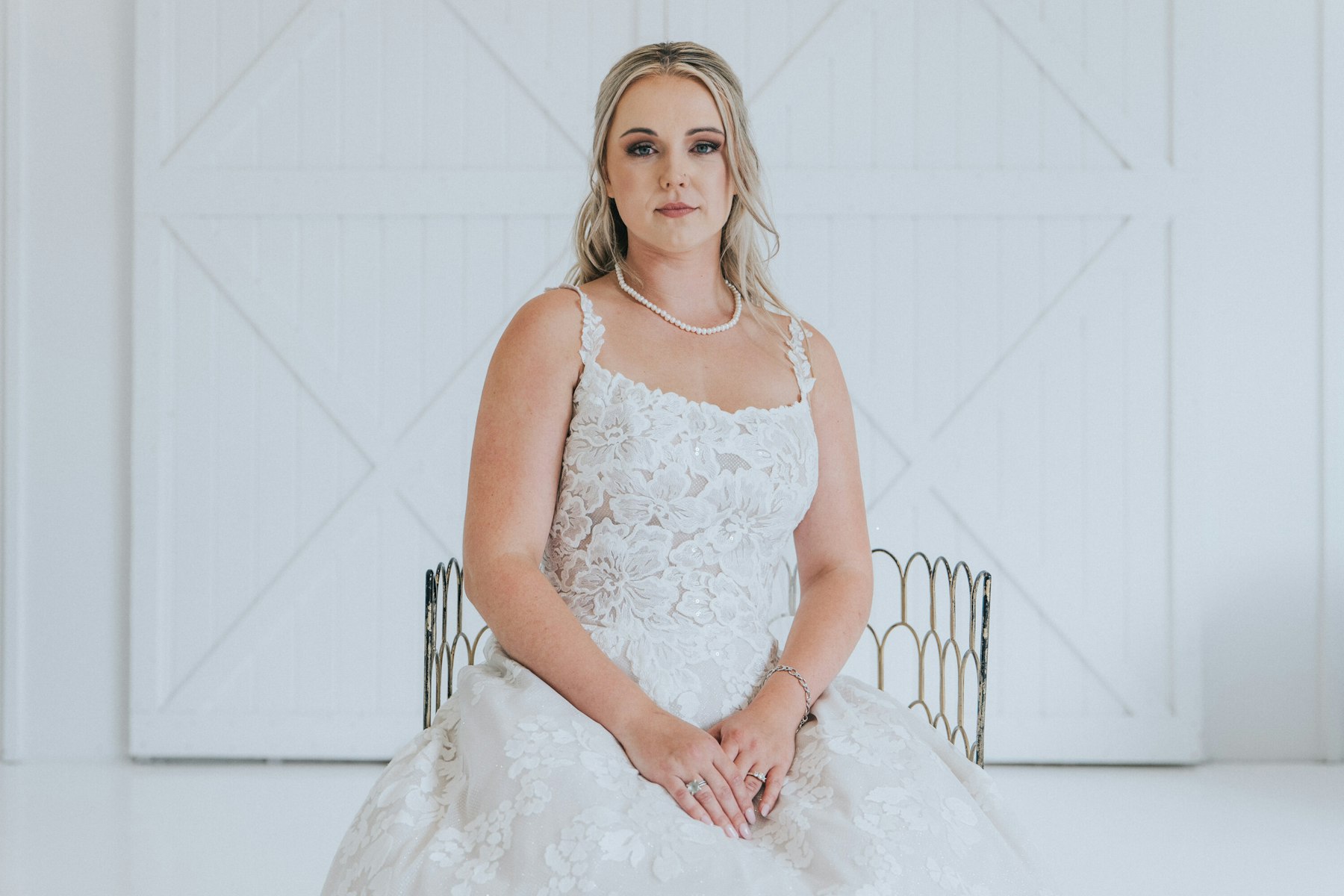 Bride seated in front of the white barn doors at a white barn wedding