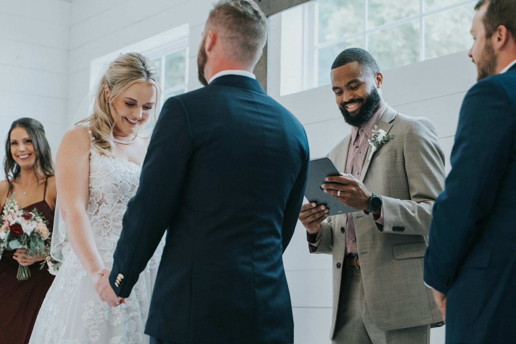 Bride and groom holding hands at the altar at a white barn wedding