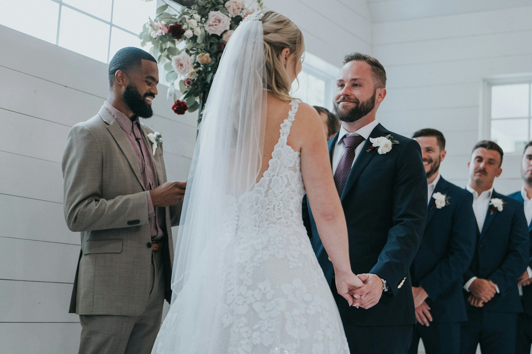 Bride and groom exchanging vows in the white chapel barn at a white barn wedding