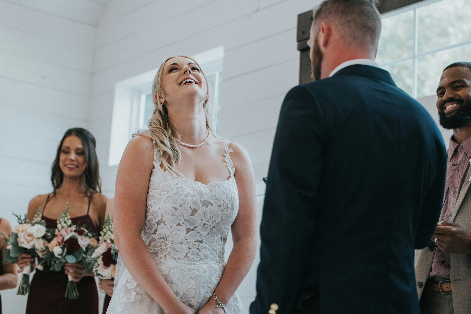 Bride laughing during the ceremony at a white barn wedding
