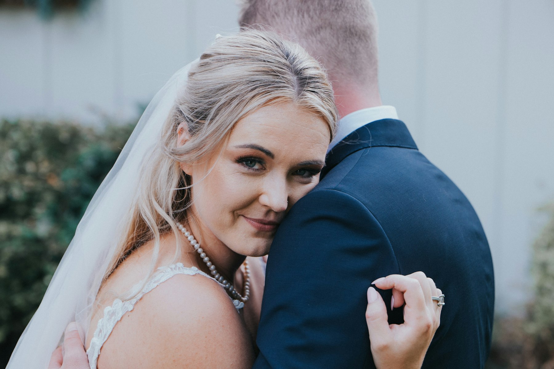 Bride resting her head on the groom's shoulder at a white barn wedding