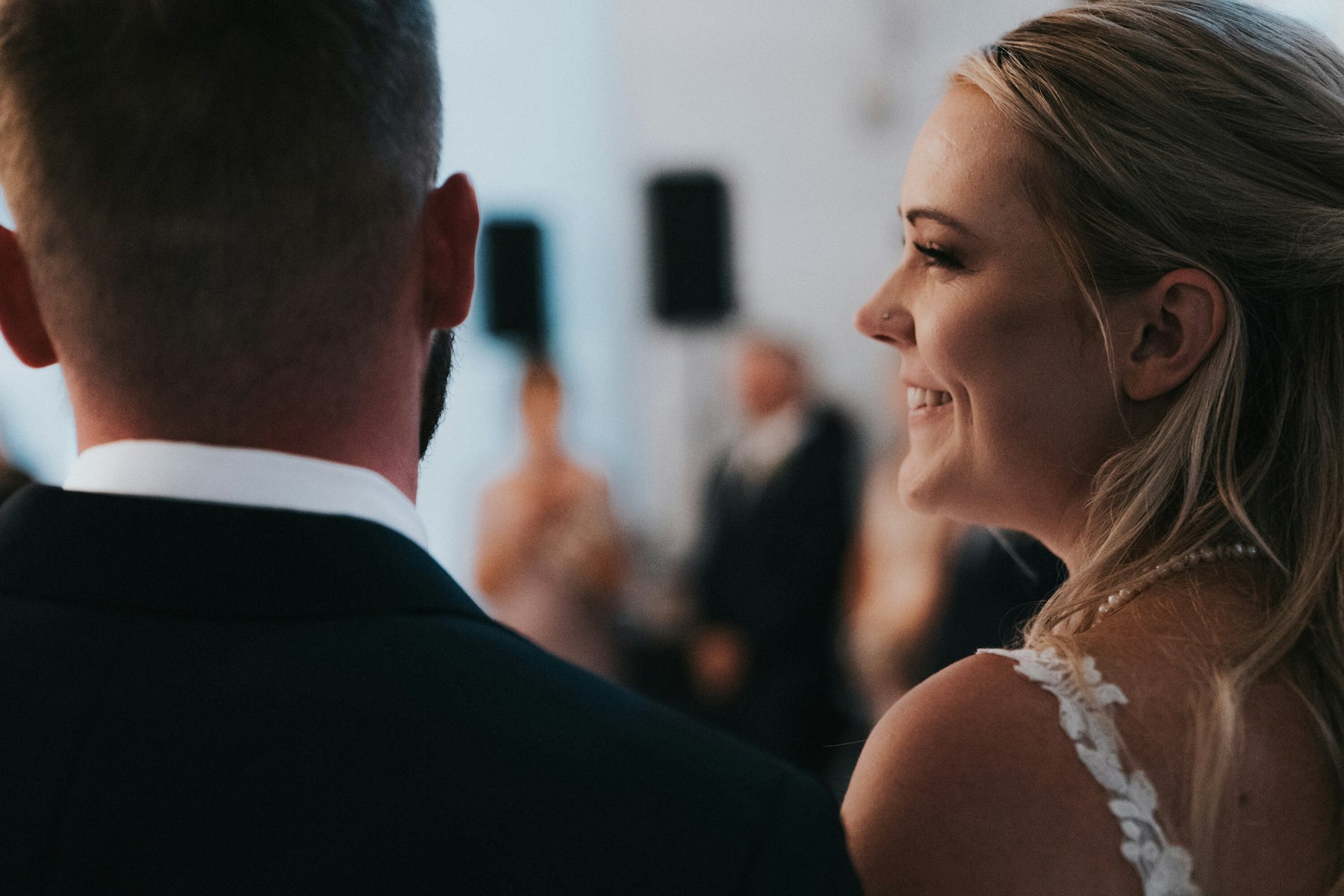 Bride smiling at the groom during the reception at a white barn wedding