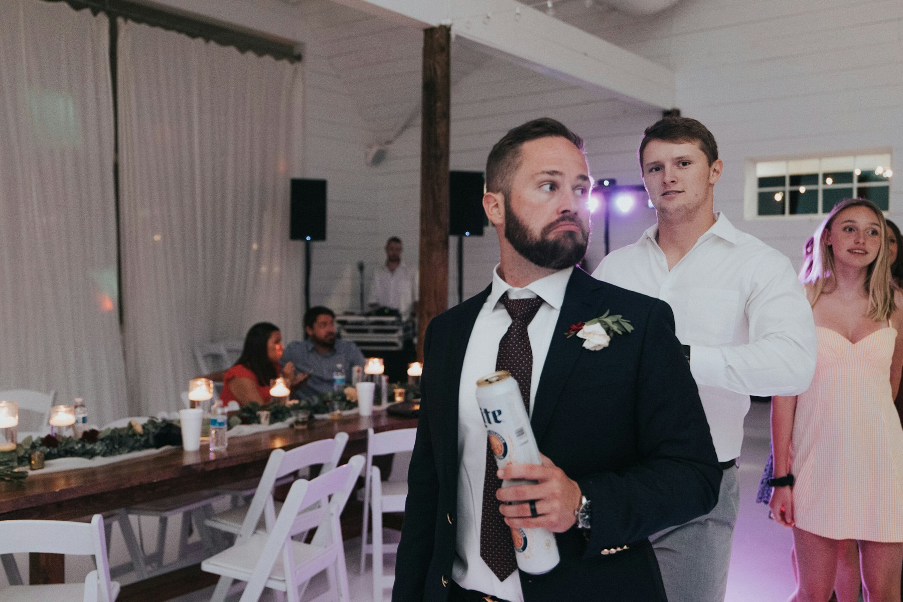 Groom with guests at the reception at a white barn wedding