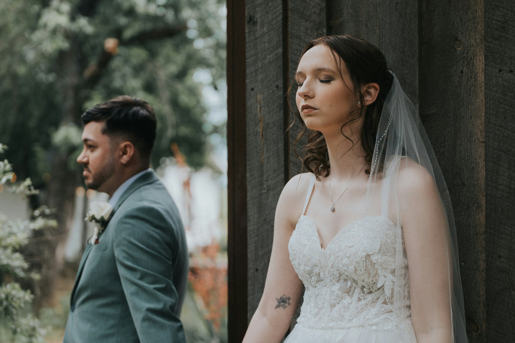 Bride and groom back to back before the first look at a rustic barn wedding