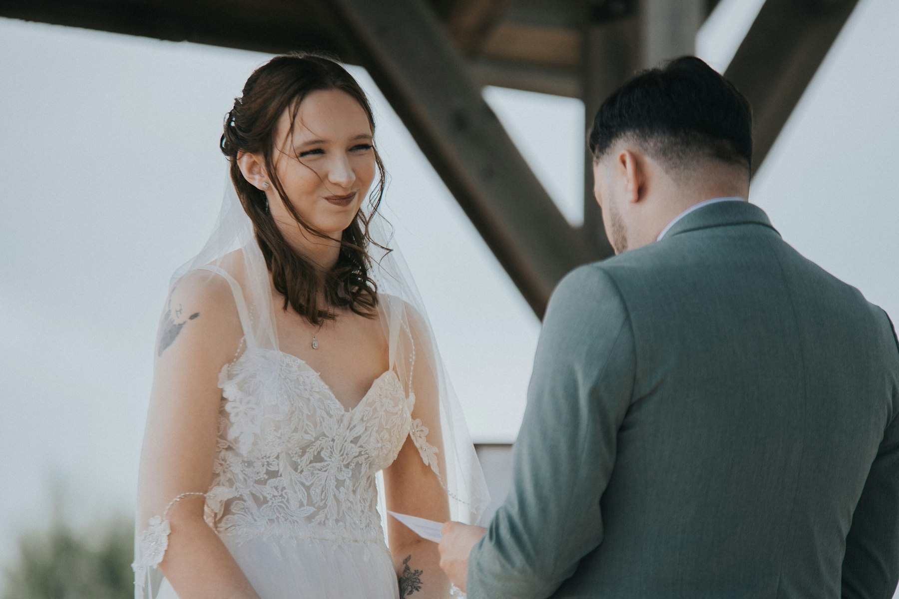 Bride smiling at the groom during the vows at a rustic barn wedding