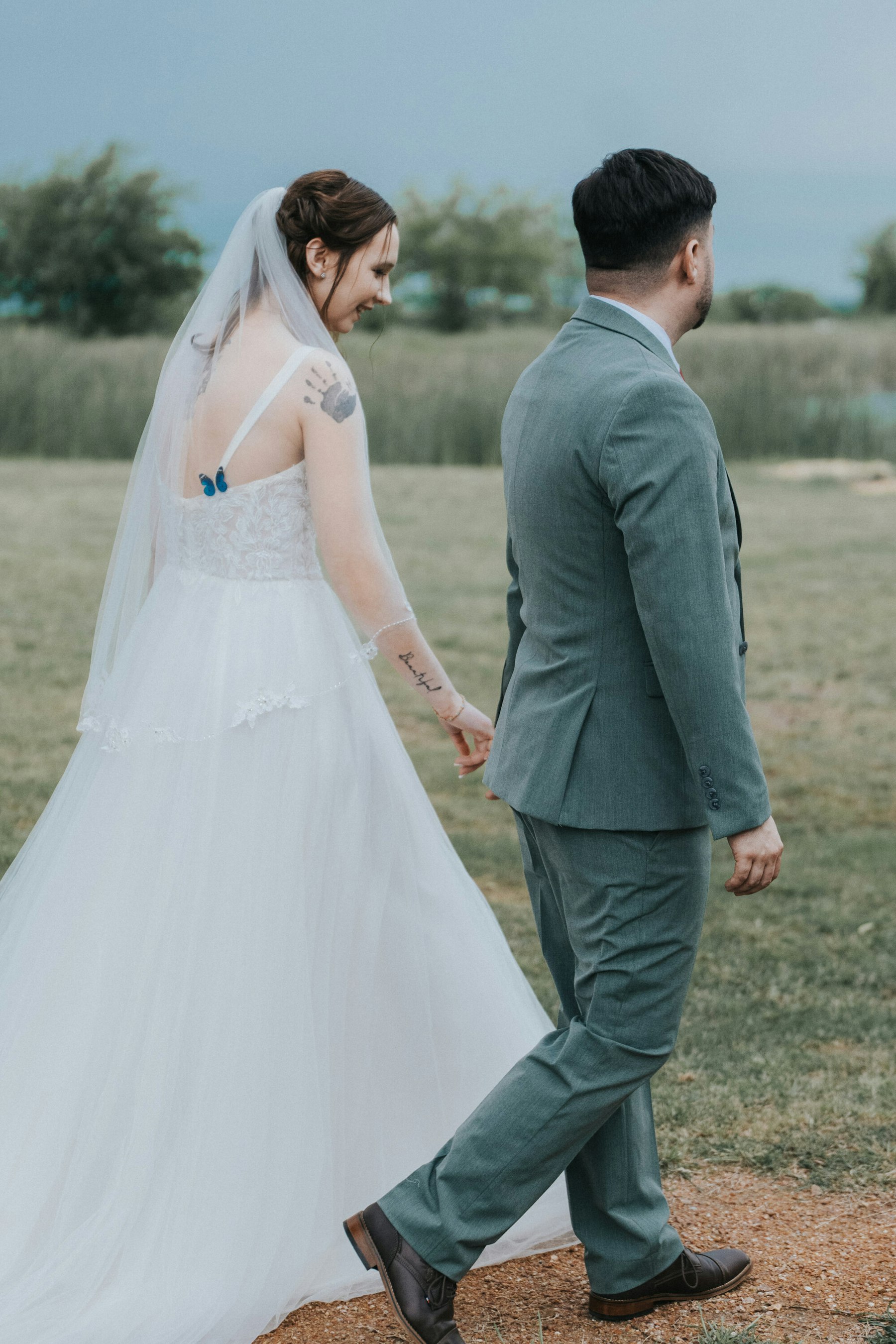 Bride and groom walking through the field at a rustic barn wedding