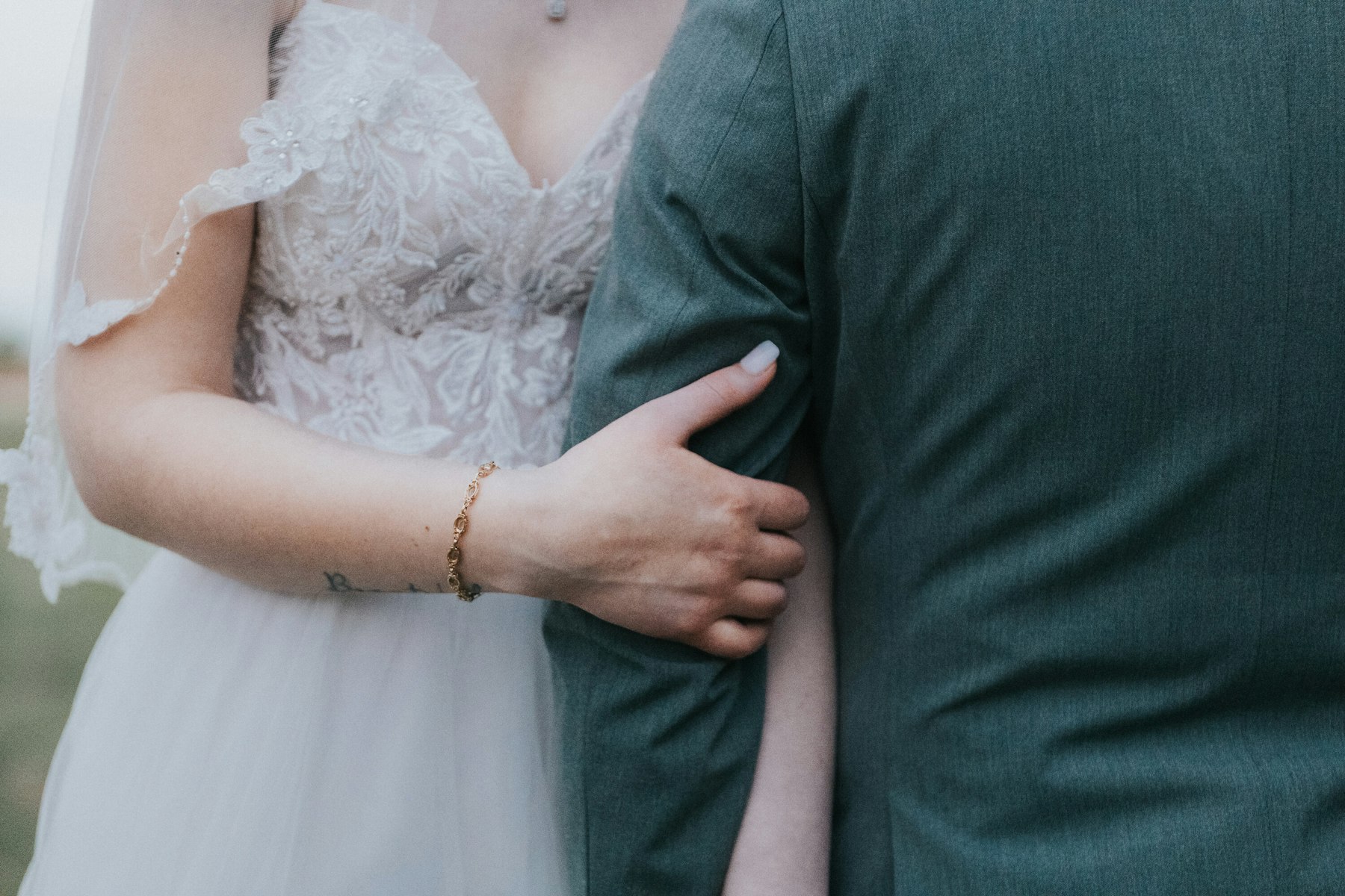 Bride's hand on the groom's arm, close up at a rustic barn wedding