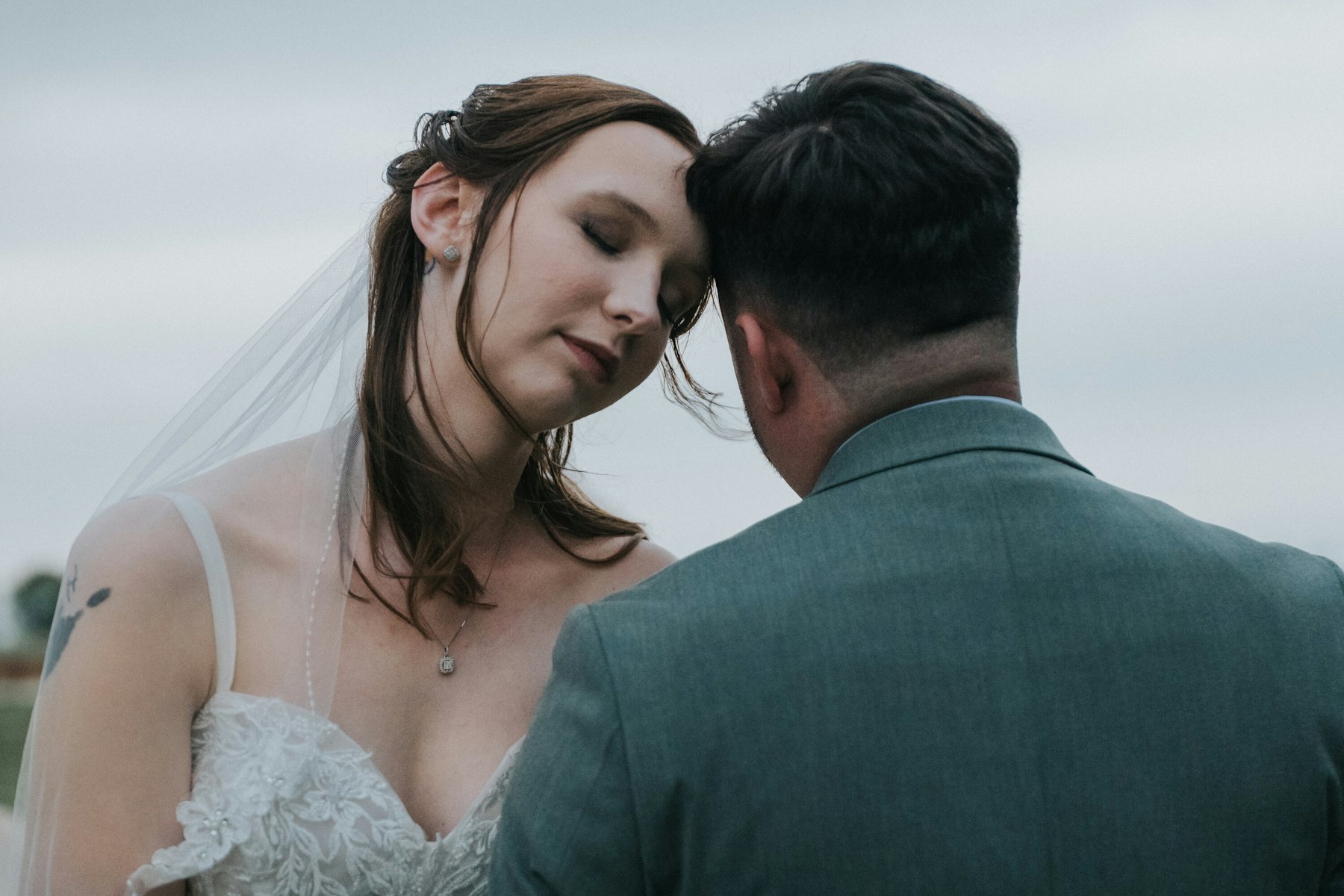 Bride resting against the groom's shoulder at a rustic barn wedding