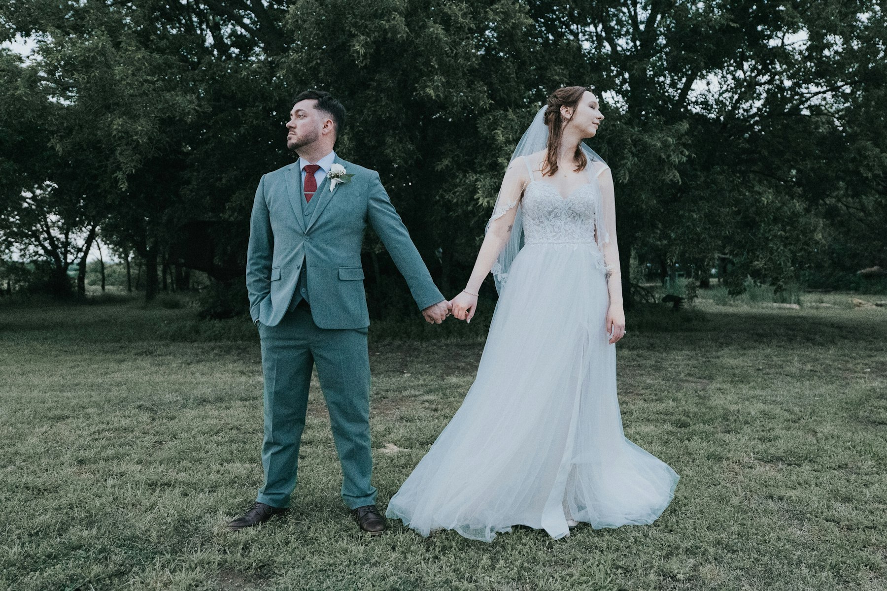 Bride and groom holding hands in the field at a rustic barn wedding