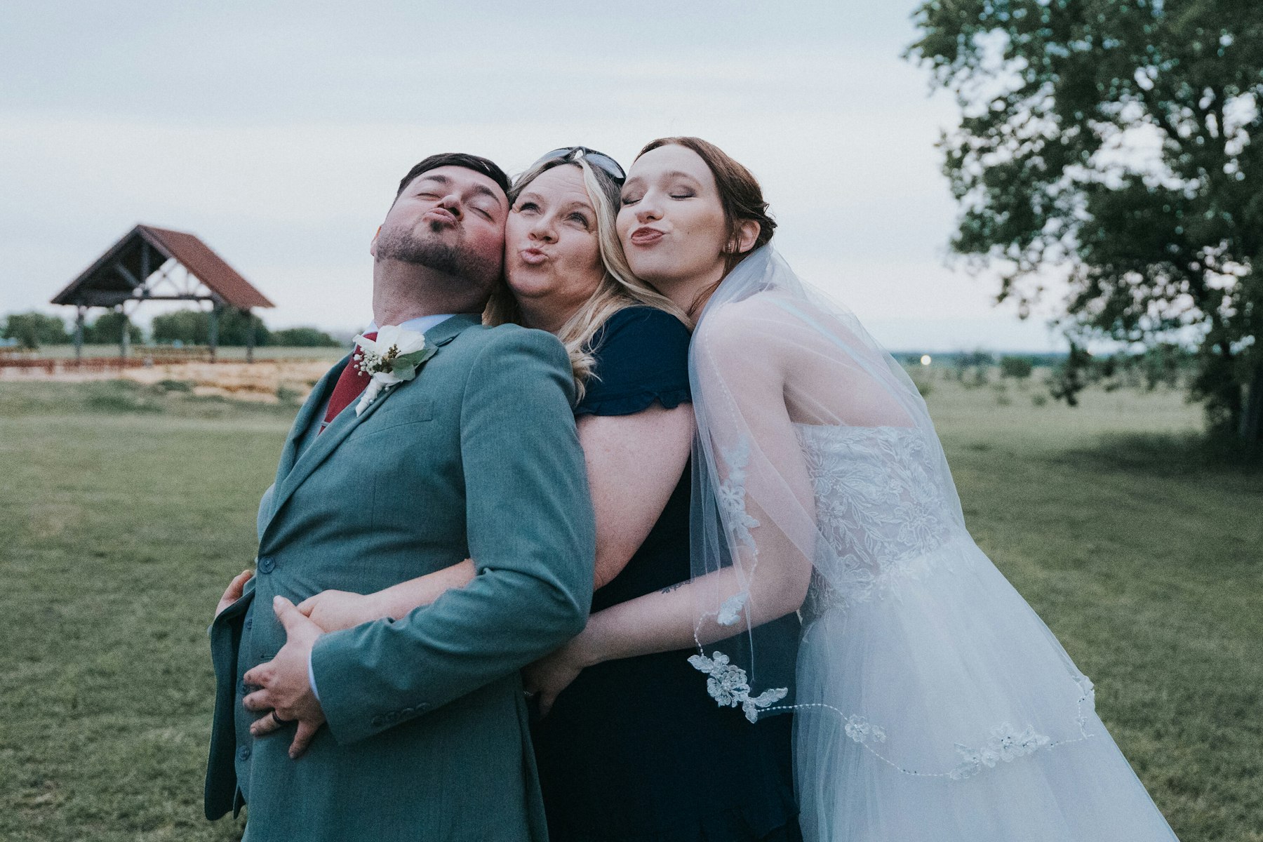 Bride and groom with a friend at the reception at a rustic barn wedding