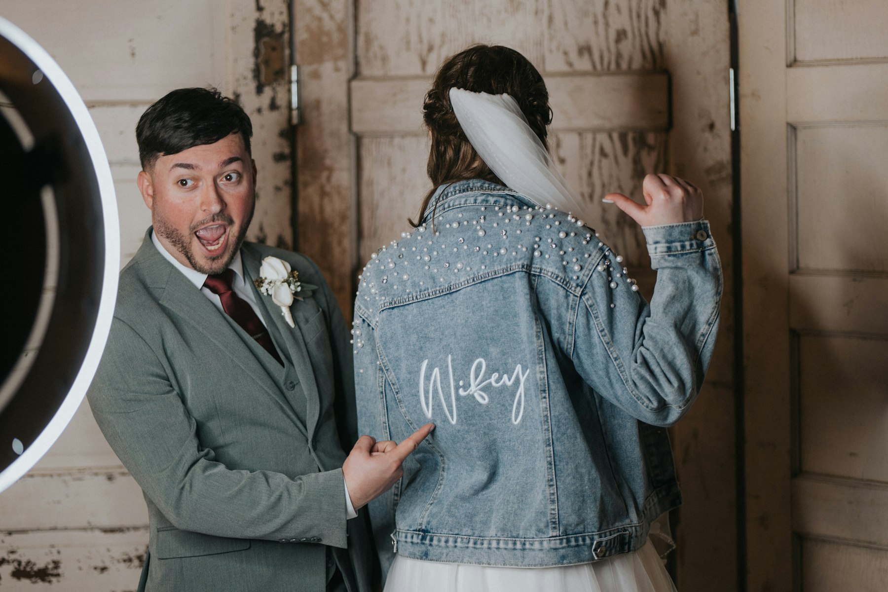 Bride showing off her Wifey denim jacket at a rustic barn wedding