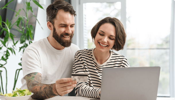 Smiling couple at laptop online shopping with bank card