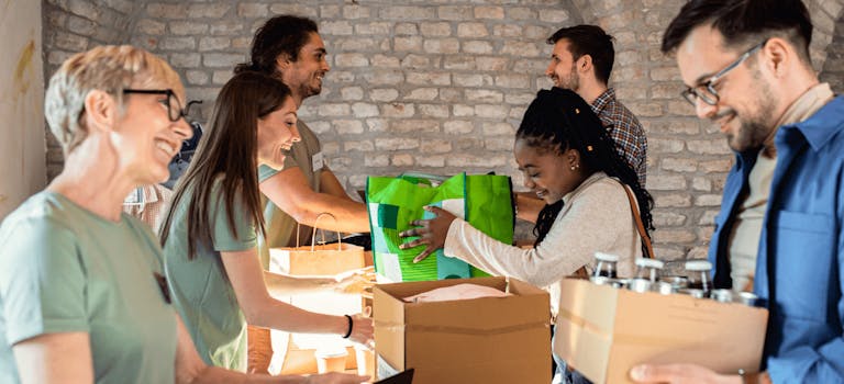 Volunteers in a food bank handing out boxes of food donations to people in need