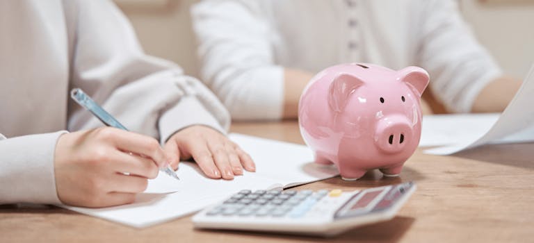 Woman doing bills with a calculator and piggy bank