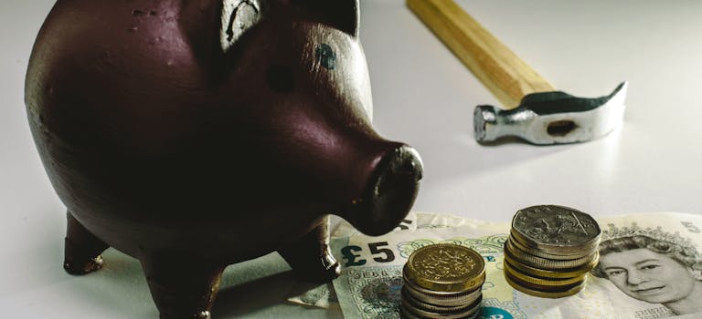 Piggy bank next to currency and hammer