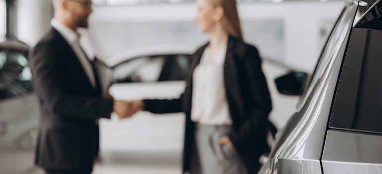 Man and woman shaking hands at a car dealership