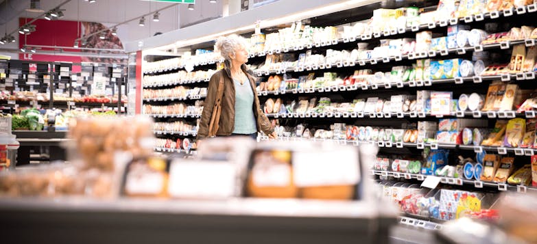Elderly woman browsing supermarket shelves
