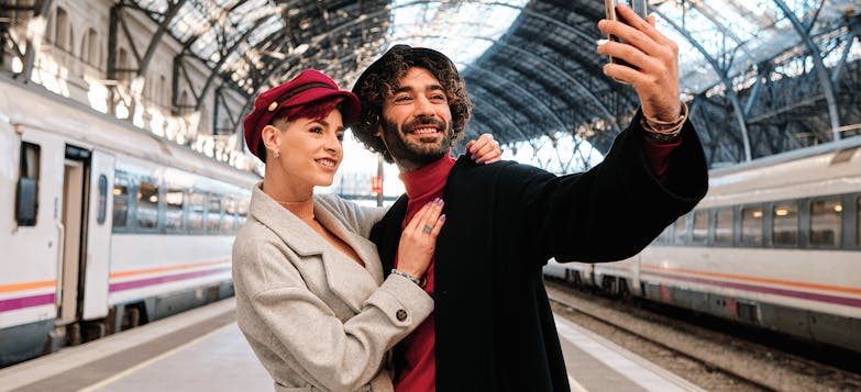 Stylish couple taking selfie at train station