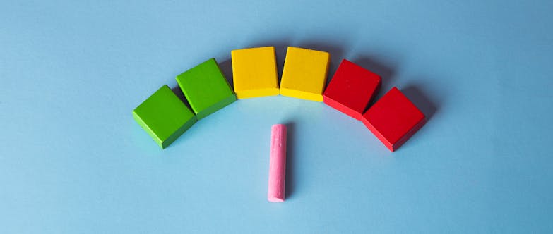 Pink chalk against blue background pointing to colourful red, yellow, green building blocks