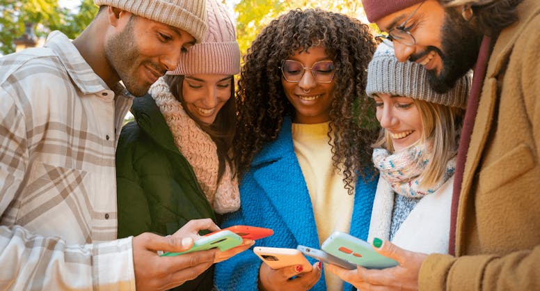 Group of young friends looking at their phones